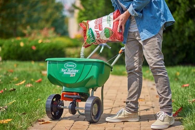 How To Revive Dead Grass: A Complete Guide 6 Pouring Fertilizer In Machine